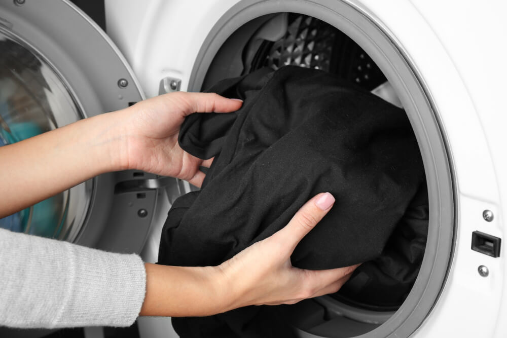 Persona lavando una playera estampada con agua fría para proteger el diseño y la tela.